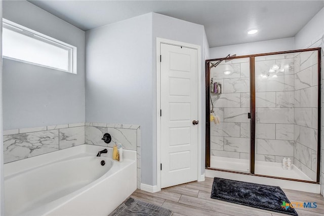 full bath with baseboards, wood finished floors, a shower stall, and a garden tub