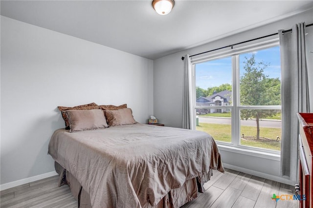 bedroom featuring light wood finished floors and baseboards