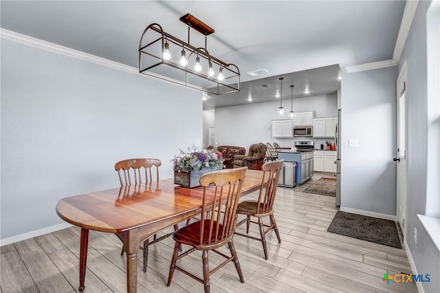 dining space featuring baseboards, visible vents, light wood finished floors, and crown molding