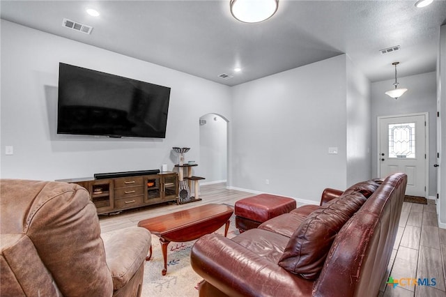 living room with visible vents, baseboards, and arched walkways