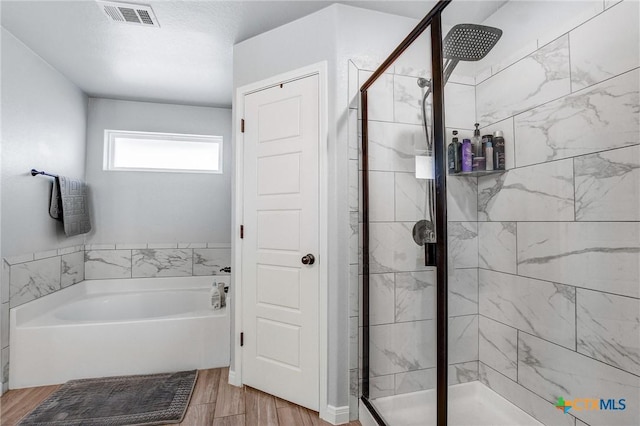 bathroom with wood finished floors, visible vents, a garden tub, and a stall shower