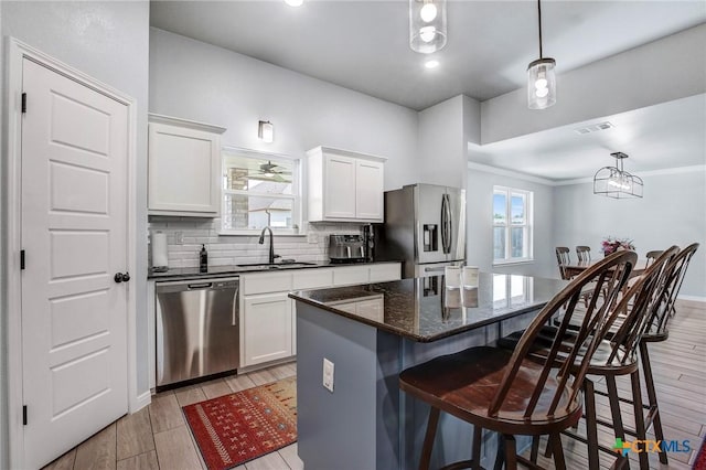 kitchen featuring a kitchen breakfast bar, tasteful backsplash, a sink, stainless steel appliances, and a center island