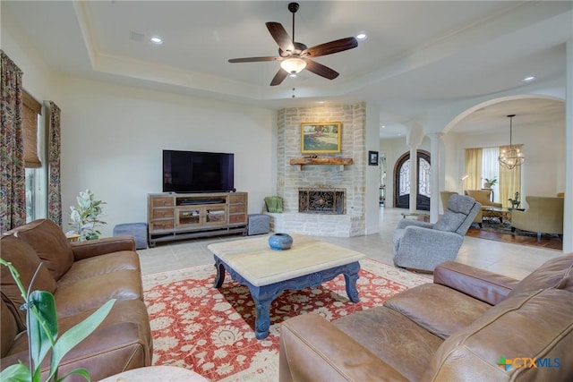 217 Foxwood, New Braunfels, TX 78132 - tiled living area featuring arched walkways, a fireplace, a raised ceiling, ceiling fan with notable chandelier, and ornate columns