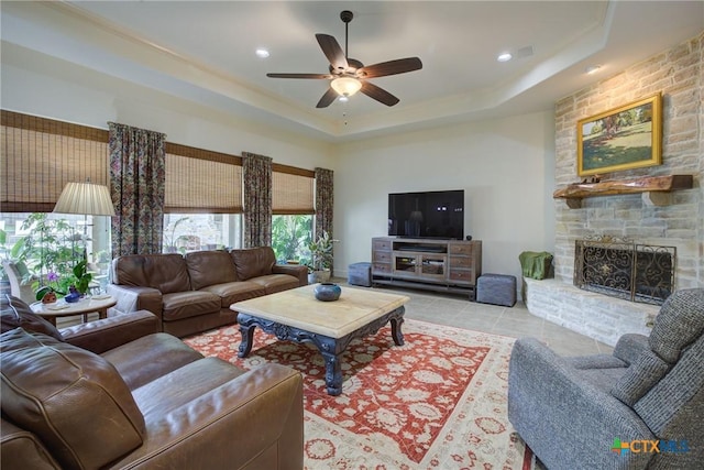 217 Foxwood, New Braunfels, TX 78132 - tiled living area featuring a ceiling fan, a tray ceiling, recessed lighting, and a stone fireplace