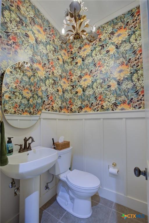 217 Foxwood, New Braunfels, TX 78132 - bathroom with toilet, a wainscoted wall, tile patterned flooring, and a decorative wall