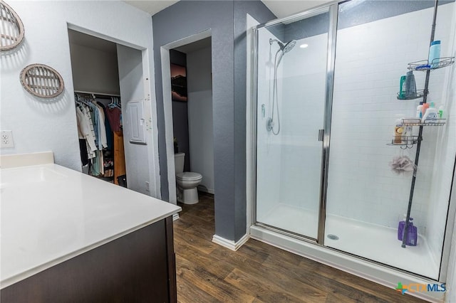 bathroom featuring a shower with shower door, toilet, wood-type flooring, and vanity