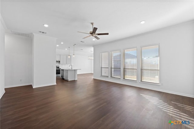 unfurnished living room featuring sink, dark wood-type flooring, ornamental molding, and ceiling fan