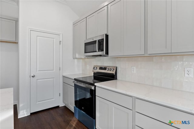 kitchen with white cabinetry, backsplash, stainless steel appliances, dark hardwood / wood-style floors, and light stone counters