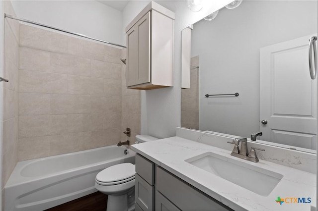 full bathroom featuring tiled shower / bath, vanity, toilet, and hardwood / wood-style floors