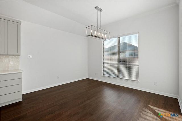 unfurnished dining area with dark wood-type flooring and a chandelier