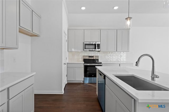 kitchen with pendant lighting, sink, stainless steel appliances, tasteful backsplash, and light stone countertops