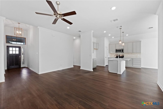 unfurnished living room with sink, ceiling fan with notable chandelier, and dark hardwood / wood-style floors