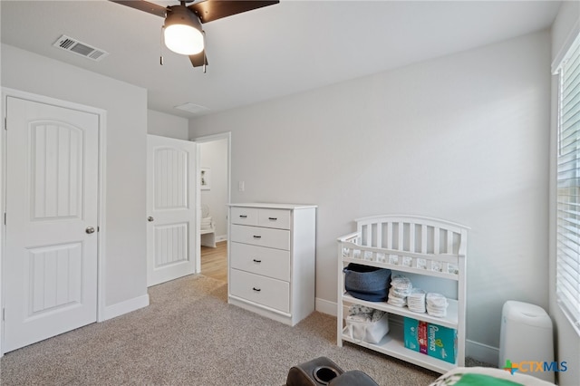 carpeted bedroom featuring a crib and ceiling fan