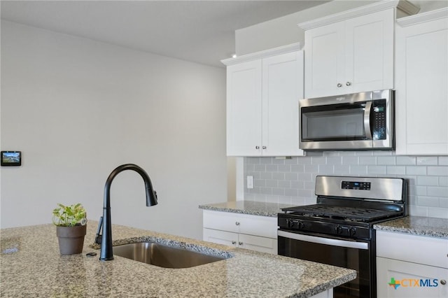 kitchen with light stone countertops, sink, tasteful backsplash, white cabinets, and appliances with stainless steel finishes