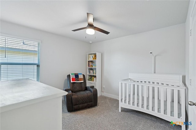 carpeted bedroom featuring ceiling fan and a nursery area