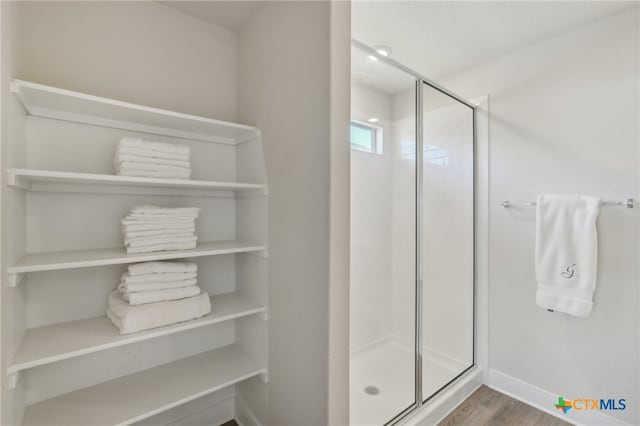 bathroom with hardwood / wood-style flooring and a shower with shower door