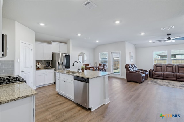 kitchen with appliances with stainless steel finishes, a kitchen island with sink, sink, light hardwood / wood-style floors, and white cabinetry