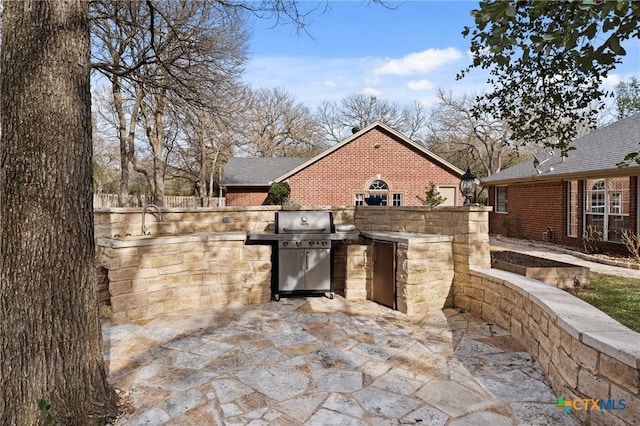 view of patio featuring exterior kitchen, area for grilling, and fence