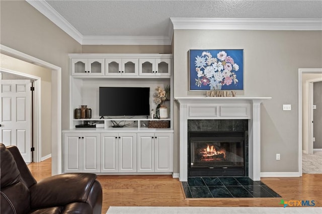 living room with light wood finished floors, a fireplace, crown molding, and a textured ceiling