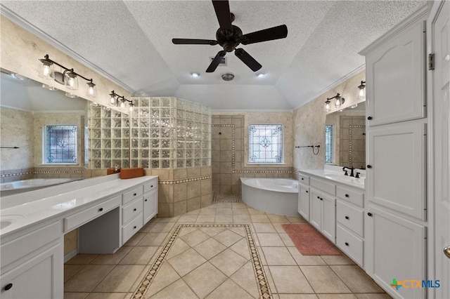 bathroom with a textured ceiling, vaulted ceiling, tile patterned flooring, and a garden tub