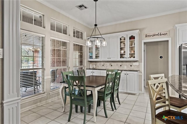 dining space with light tile patterned floors, a notable chandelier, visible vents, baseboards, and ornamental molding