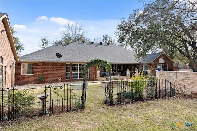 view of front facade featuring a shingled roof, fence private yard, a patio area, and brick siding