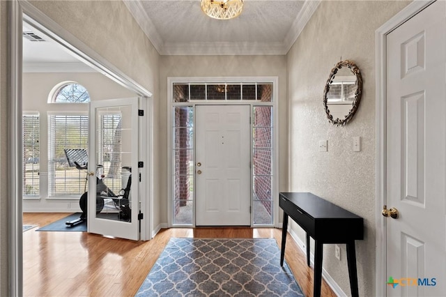 foyer entrance featuring wood finished floors, a wealth of natural light, and crown molding