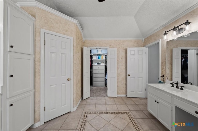 bathroom featuring a textured ceiling, tile patterned flooring, vanity, vaulted ceiling, and ornamental molding