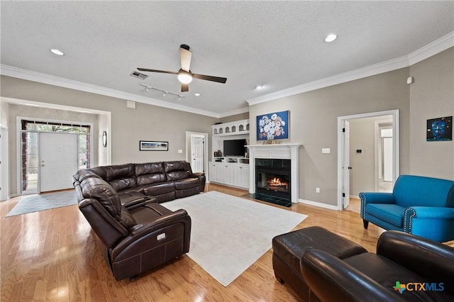 living room featuring light wood finished floors, crown molding, visible vents, and a textured ceiling