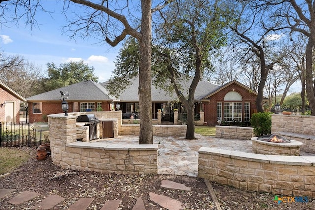 exterior space with brick siding, area for grilling, a patio area, fence, and a fire pit