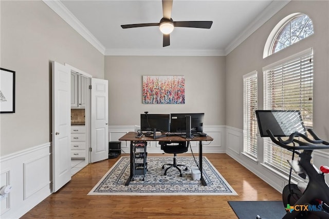 office area featuring ceiling fan, a wainscoted wall, crown molding, and wood finished floors