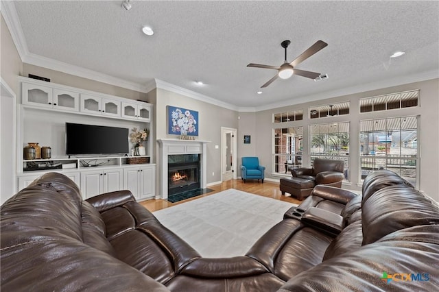 living area featuring a high end fireplace, crown molding, light wood-style flooring, and a textured ceiling