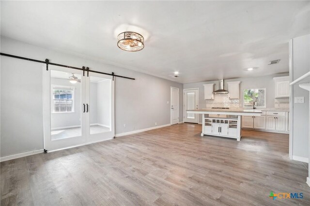 801 E Johnson St, Burnet, TX 78611 - kitchen featuring a barn door, wall chimney range hood, light countertops, decorative backsplash, and baseboards