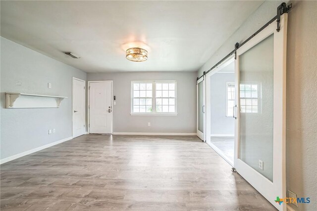 801 E Johnson St, Burnet, TX 78611 - unfurnished living room with a barn door, wood finished floors, and baseboards