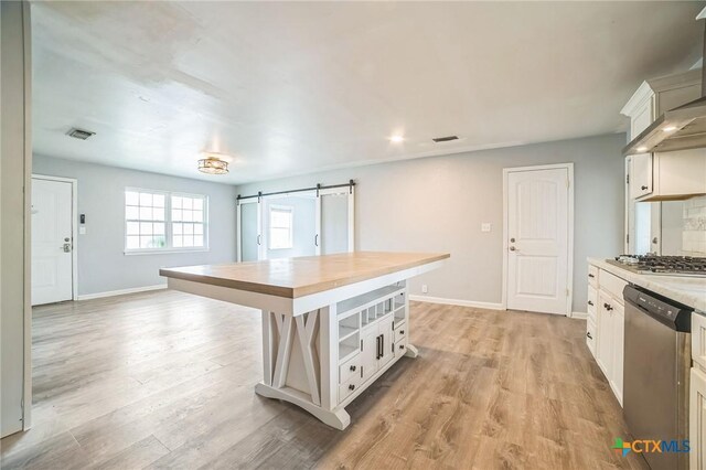 801 E Johnson St, Burnet, TX 78611 - kitchen featuring appliances with stainless steel finishes, butcher block countertops, light wood-type flooring, baseboards, and a barn door