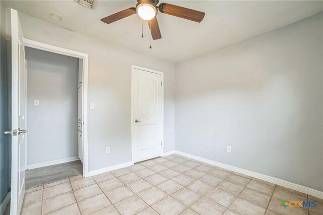 801 E Johnson St, Burnet, TX 78611 - unfurnished bedroom with light tile patterned floors, a ceiling fan, and baseboards