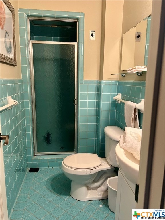 bathroom with toilet, a shower with door, tile walls, tile patterned flooring, and vanity