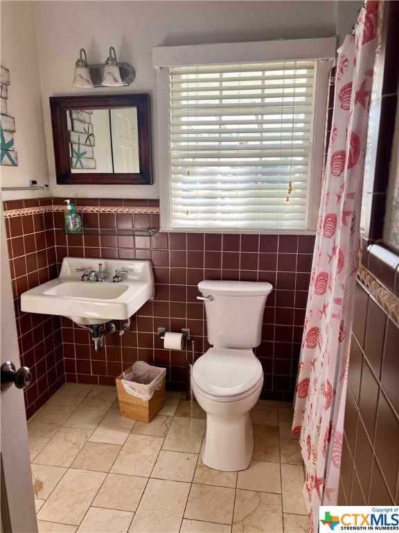 bathroom featuring a wealth of natural light, sink, tile walls, and toilet