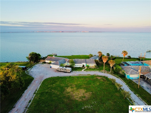 aerial view at dusk featuring a water view