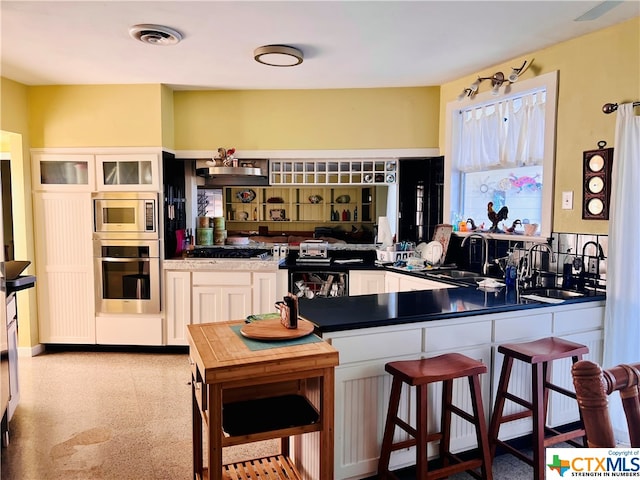 kitchen with kitchen peninsula, white cabinets, sink, and stainless steel appliances