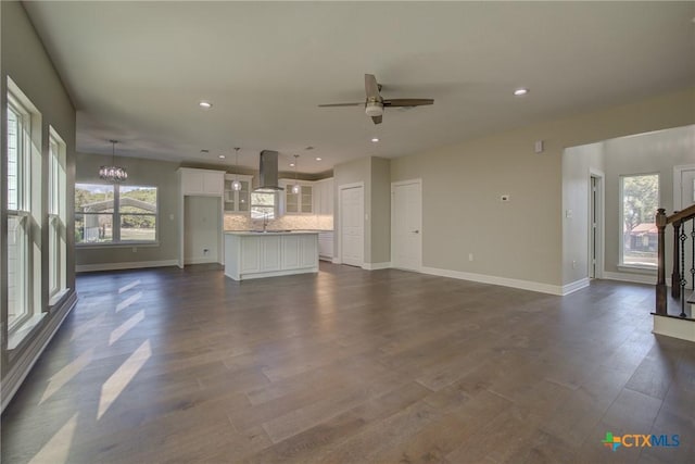 unfurnished living room with ceiling fan with notable chandelier, dark hardwood / wood-style flooring, and sink