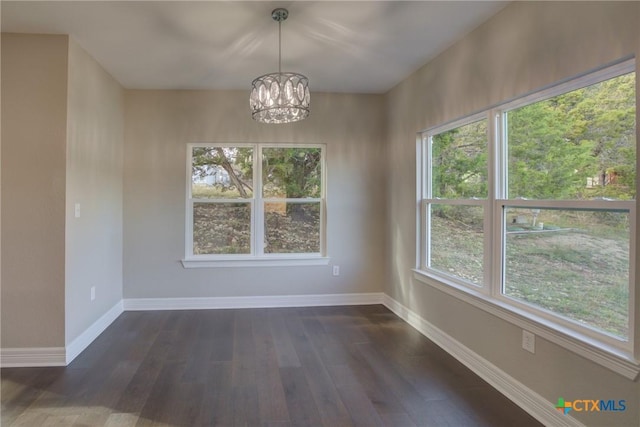 unfurnished dining area with plenty of natural light, dark hardwood / wood-style flooring, and a chandelier