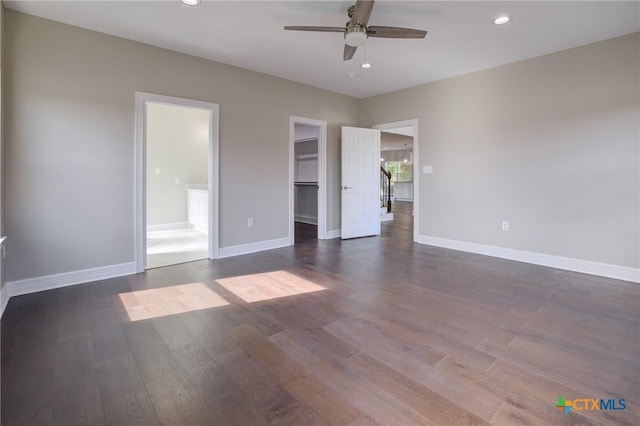 unfurnished bedroom featuring dark hardwood / wood-style floors, ceiling fan, a walk in closet, and a closet