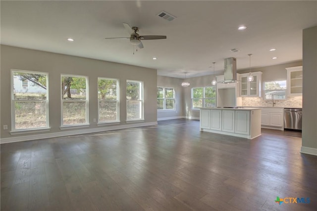 unfurnished living room featuring dark hardwood / wood-style floors, a healthy amount of sunlight, and ceiling fan with notable chandelier