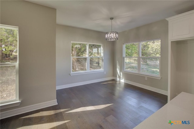 unfurnished dining area with a chandelier and dark wood-type flooring