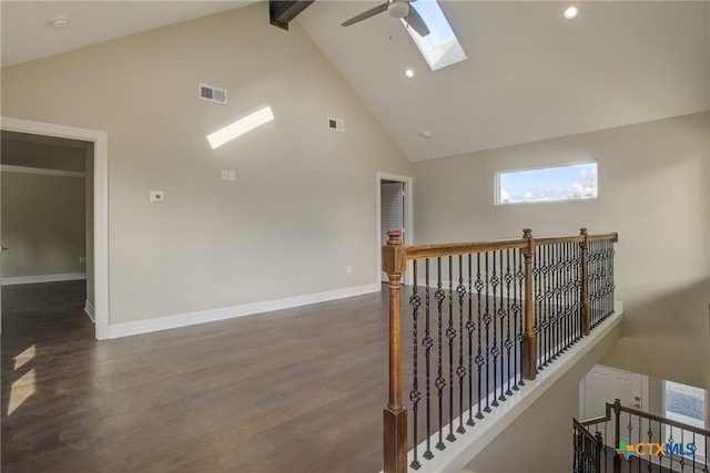 hall with beamed ceiling, dark hardwood / wood-style floors, high vaulted ceiling, and a skylight