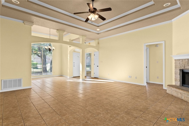 unfurnished living room featuring a tray ceiling, crown molding, light tile patterned floors, and ceiling fan with notable chandelier