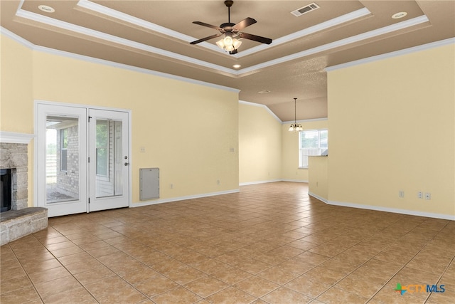 unfurnished living room featuring ceiling fan with notable chandelier, crown molding, light tile patterned floors, a fireplace, and a tray ceiling