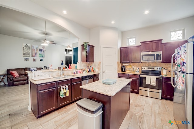 kitchen with appliances with stainless steel finishes, tasteful backsplash, sink, and a kitchen island