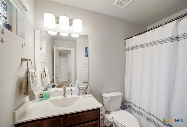 bathroom with vanity, toilet, and a textured ceiling